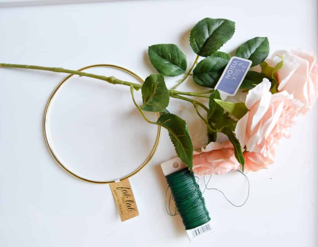 Supplies needed to make a DIY flower crown. One stem of silk flowers, wire, and a gold crafting hoop are all you need to make a flower crown.