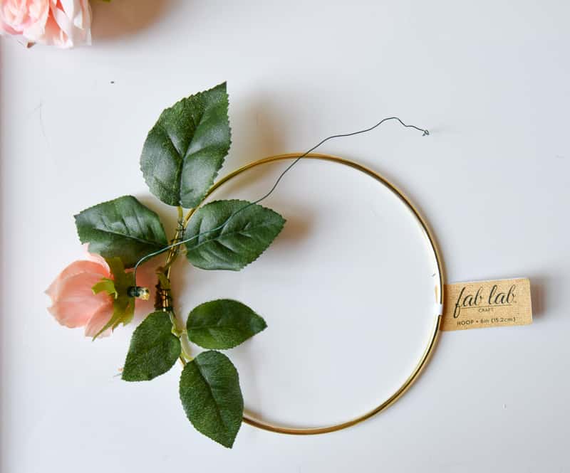 Step three in making a floral crown is attaching the peony flower heads with wire. Wrap floral wire around the base of the flower head and attach it to the macramé hoop.