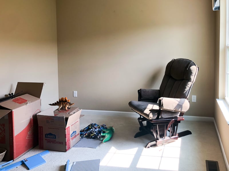 Before picture of little girl's room before renovating with tan walls and boxes of clutter