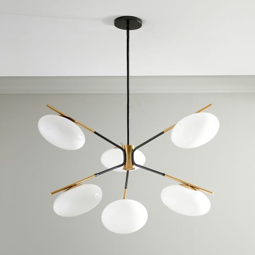 A modern chandelier with six oval globe lights attached to black and gold metal chandelier spokes.