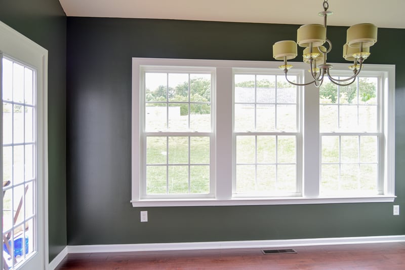 A photo of a room with walls painted green using Behr north woods, a window, and chandelier.