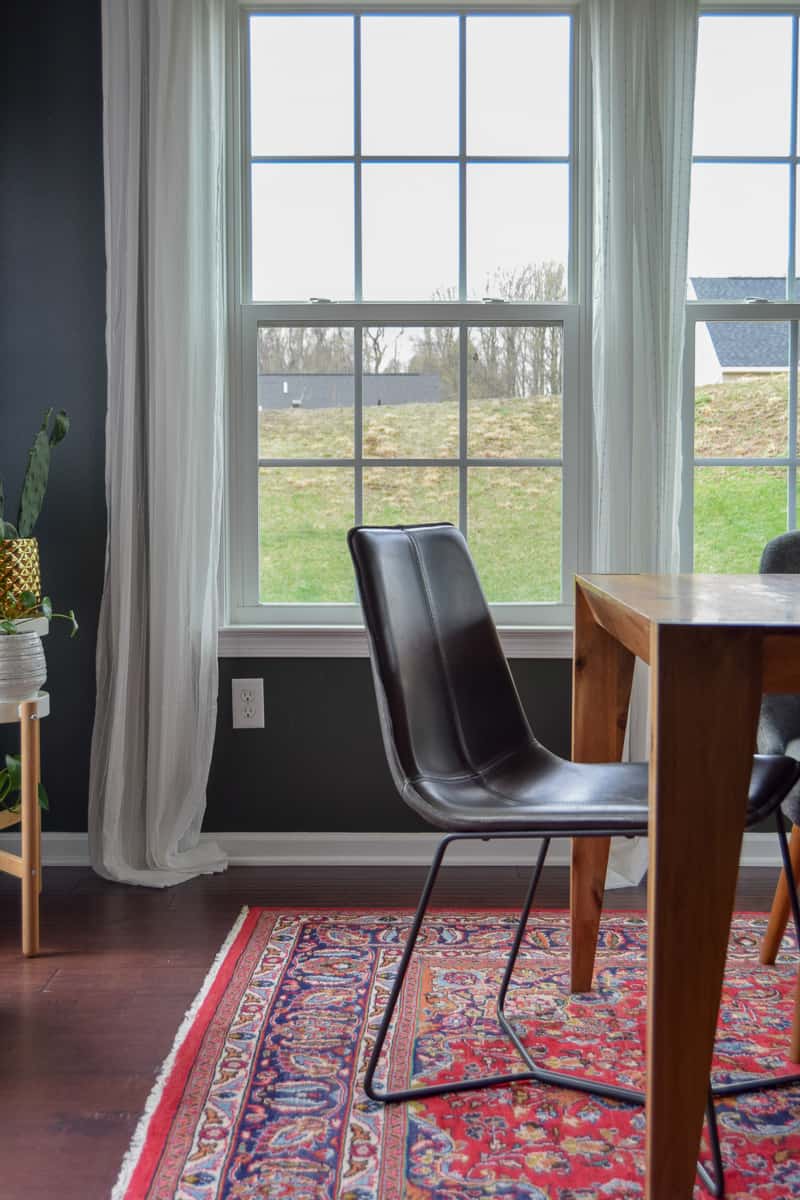 Modern chairs used in tandem with other benches and chairs on a rug over hardwood floors with curtains