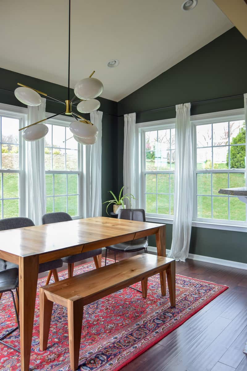 Beautiful wooden dining room table over a rug with mismatched chairs that shows off mid century ideas