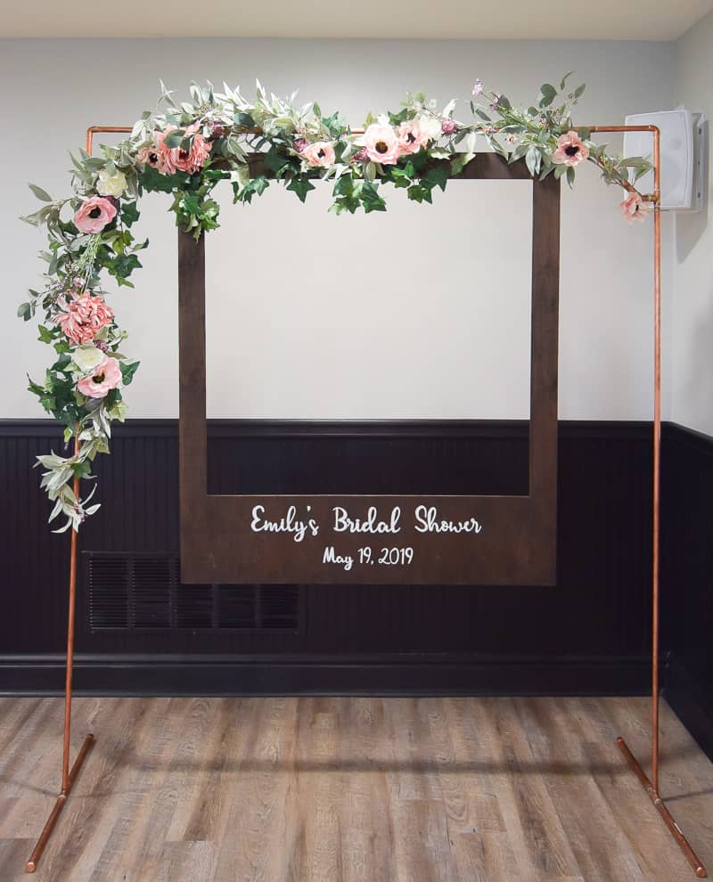 A completed look at the DIY polaroid photobooth created for my sister's bridal shower! We built a copper frame, decorated with with flower garland, and made a oversized polaroid picture frame with a sheet of plywood.