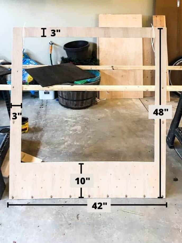 A sheet of plywood cut out into the shape of an oversized polaroid frame. Black marks on the image show the frame measurements.