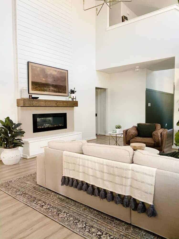 This massive wood accent wall is dramatic with floor to ceiling shiplap installed above the fireplace in this two story living room concept from Love & Renovations