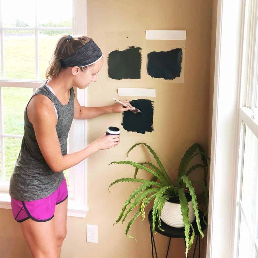 A woman is painting black on a wall.