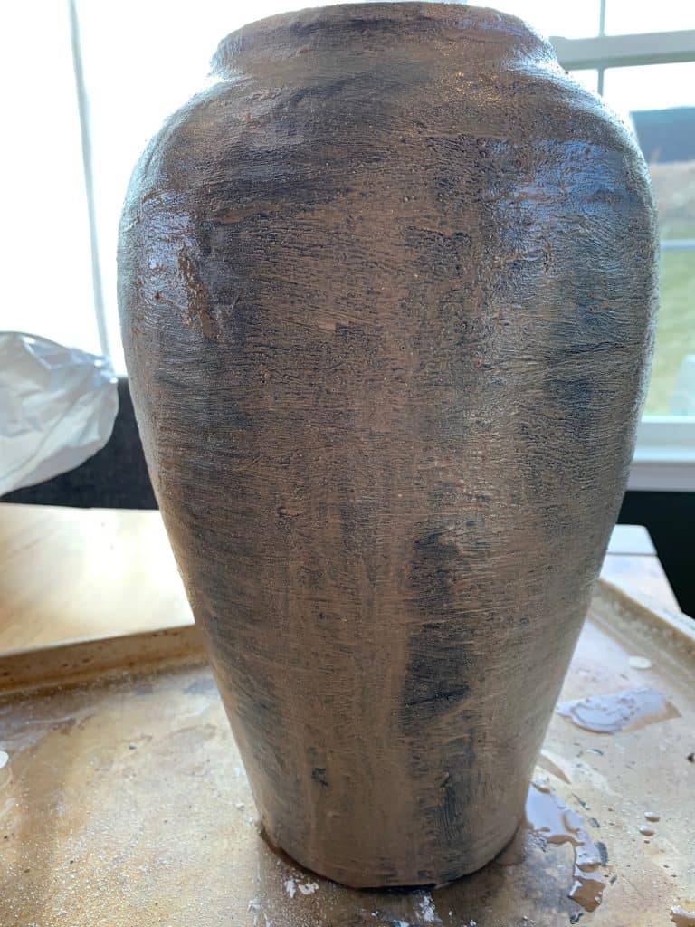 A vintage vase, coasted in plaster, black paint, and lime wash, giving it an aged black pottery finish.