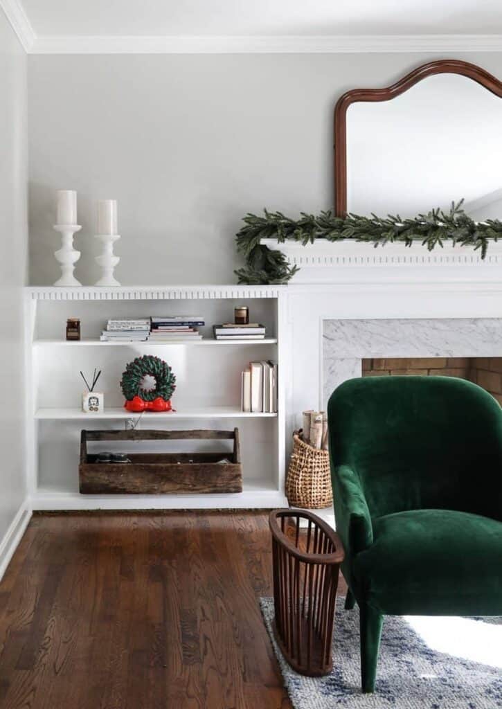 A living room scene with white wood built in bookshelves and a white mantel decorated for Christmas. The walls are painted with Agreeable Gray - a grey-beige color.