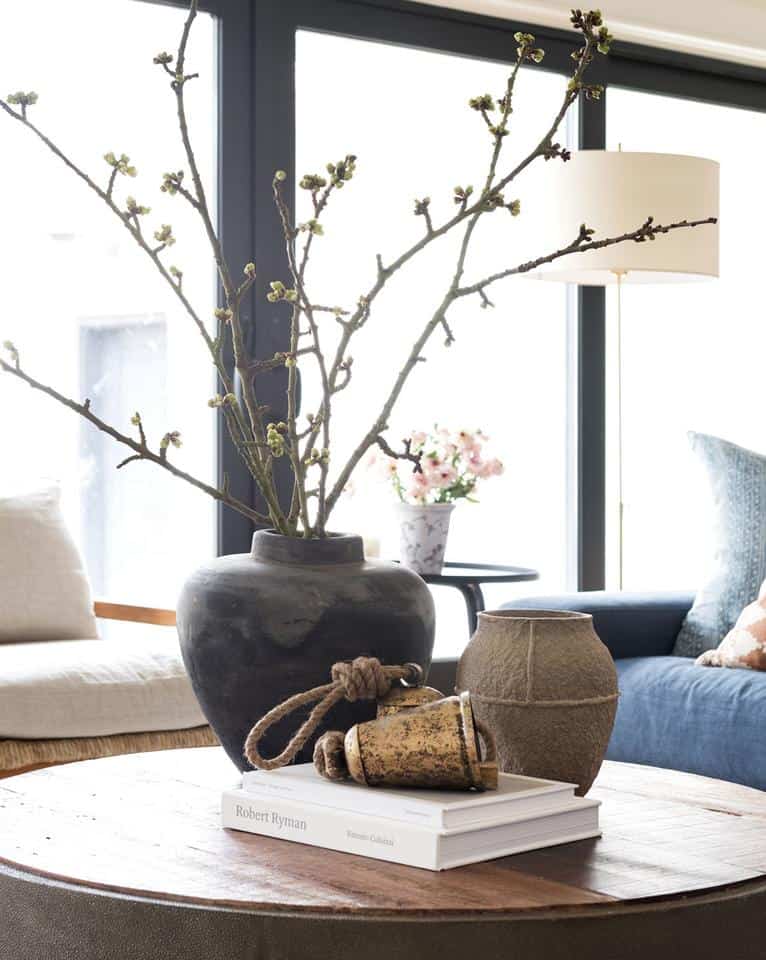 Pottery is popular in decor lately, This living room table centerpiece is composted of two large vintage vases and stacked books.