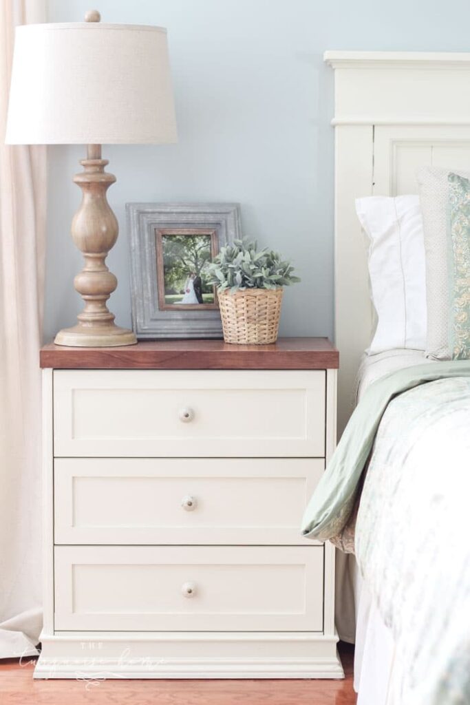 A photo of bedside table and headboard painted in Sherwin Williams top white paint color - Antique White.