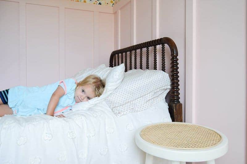 Target stool painted and placed next to a bed to be used as a night stand as a creative idea