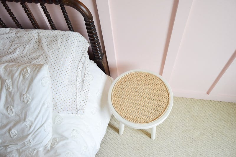 Looking for DIY nightstand ideas? I tried my hand at DIY cane projects with a DIY cane nightstand for Evie’s toddler girl room! I used a stool from Target, some spray paint, and cane to make a DIY nightstand. It’s the perfect addition to a little girl’s room if you’re looking for girl room ideas. The DIY cane nightstand was an easy DIY that adds tons of style and function to her girly room. #cane #canefurniture #diyprojects #diycanenightstand
