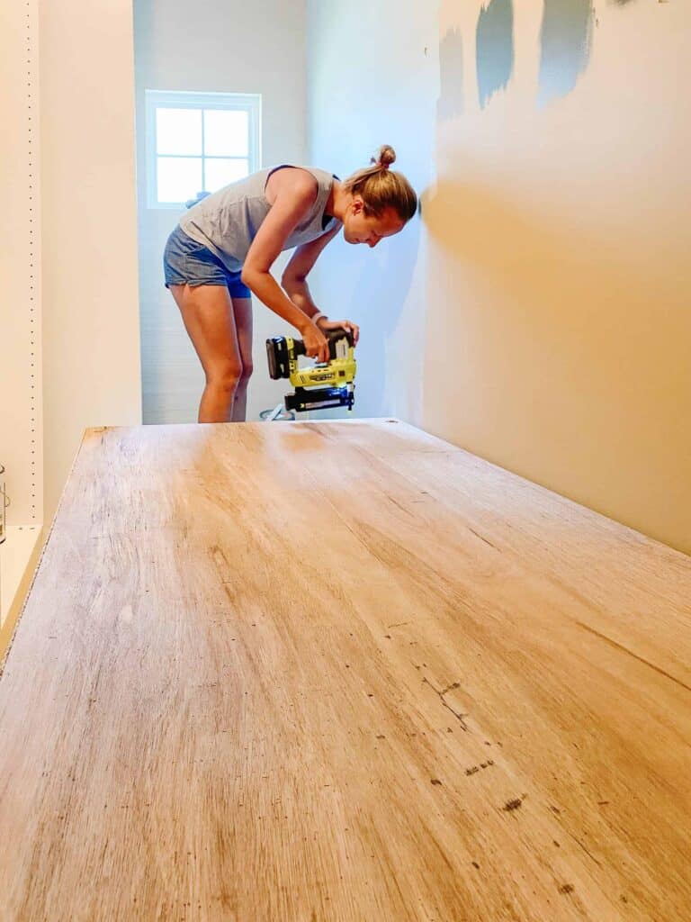 A women installing plywood on the back of the wardrobe for the closet.