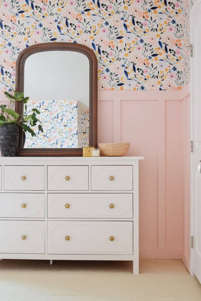 Simply White by Benjamin Moore painted on a white dresser cabinet with a vintage wooden mirror, a potted plant, and various other accessories placed on its surface.