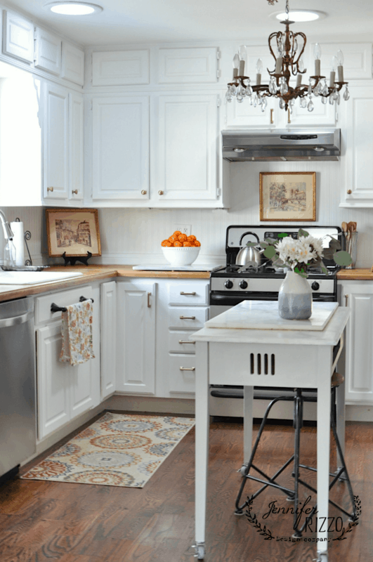 Kitchen cabinets painted with Simply White by Benjamin Moore, featuring white cabinets with built-in lighting and chandeliers.