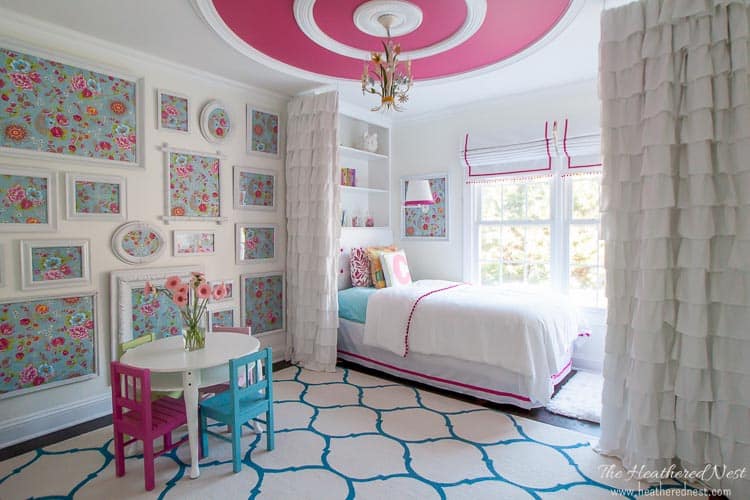 A cute bedroom featuring Simply White by Benjamin Moore Paint Color walls that are offset by the pink color and 4 mini chairs and a table.