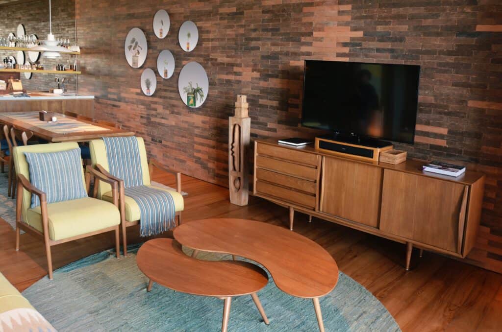 This living room shows the mid-century interior style. Using rich wood furniture, organic and geometric shapes (with the kidney bean shaped coffee tables) and angeled or tapered legs on the furniture. 