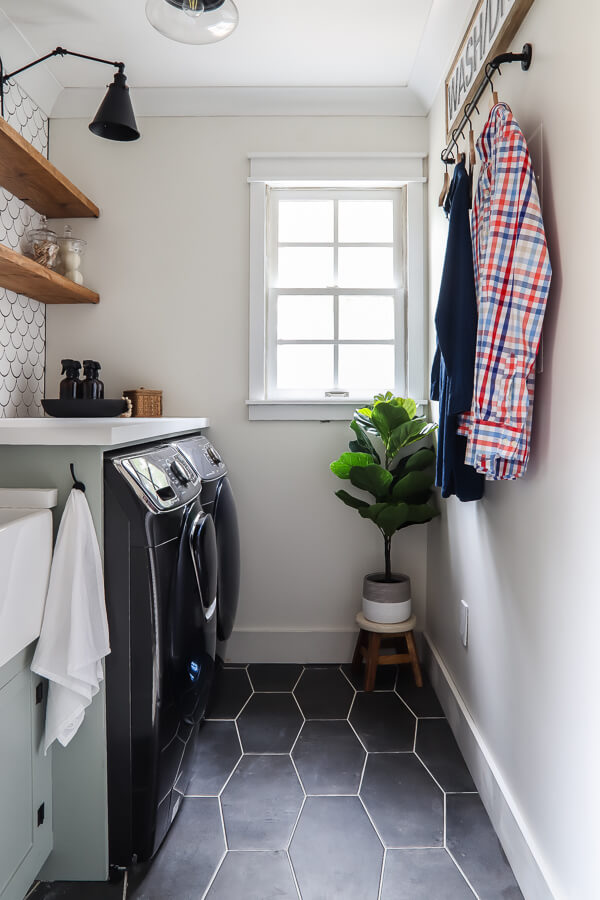 Small laundry room window painted with SW Alabaster on the walls, black tile floors and tiled scallop wall behind the washer and dryer