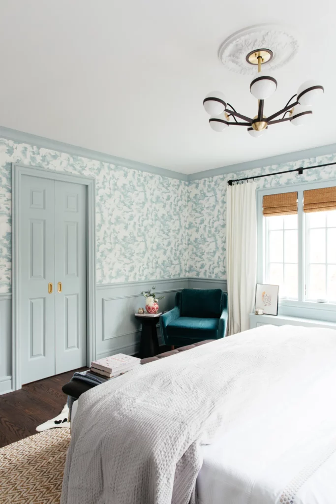 BM Smoke blue green paint color used on crown molding, wainscoting paneling and doors with matching patterned wallpaper in a bedroom