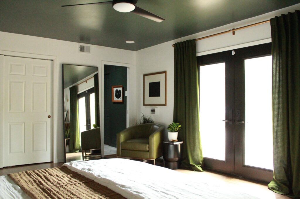 A room with a green ambiance, furnished with a mirror and curtain.