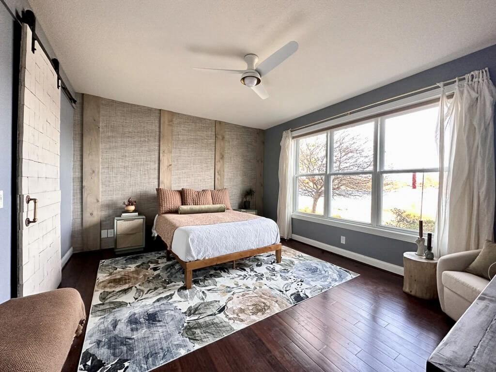 A pretty floral patterned rug in 8x10 size under this Queen size bed with ceiling fan on the bedroom.