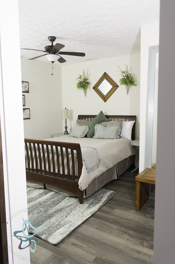 A small rug, like the one Designed Decor uses in this guest bedroom, can be placed under a bed to add warmth and texture.