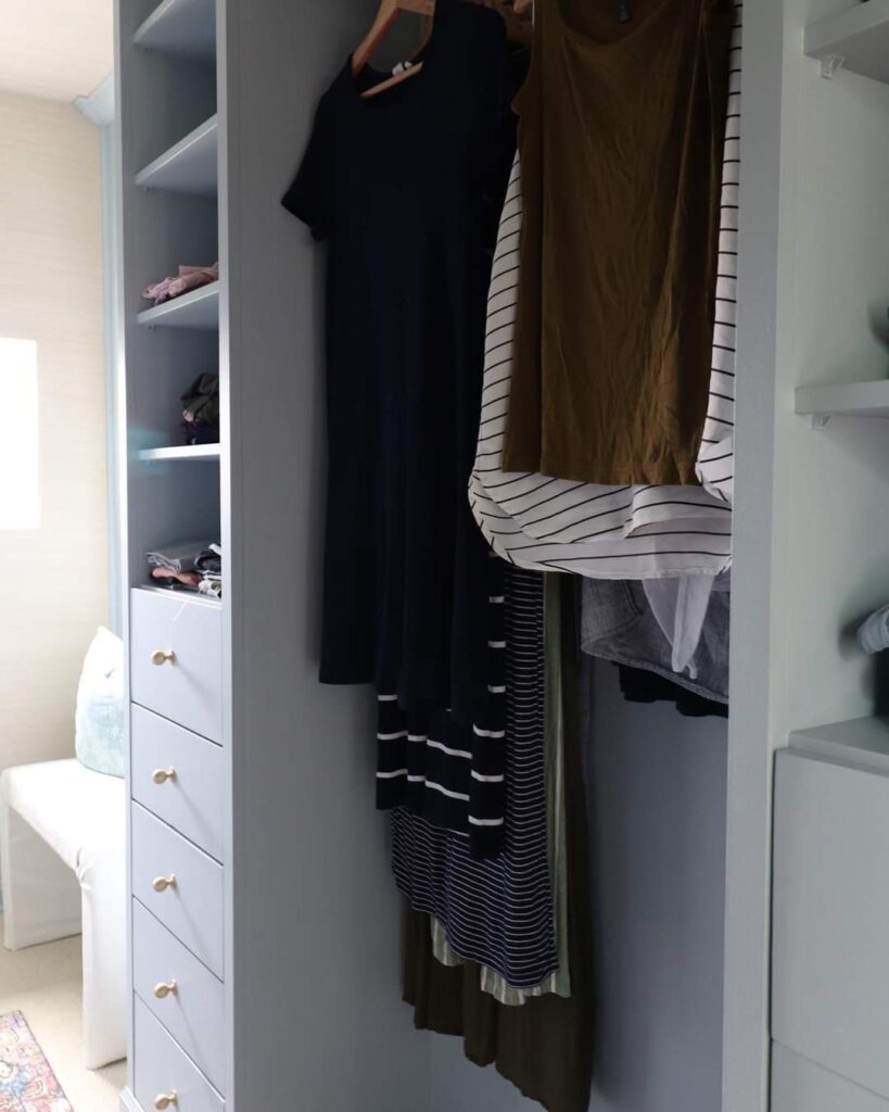 A close-up photo of a closet cabinet with some clothes hanging inside.