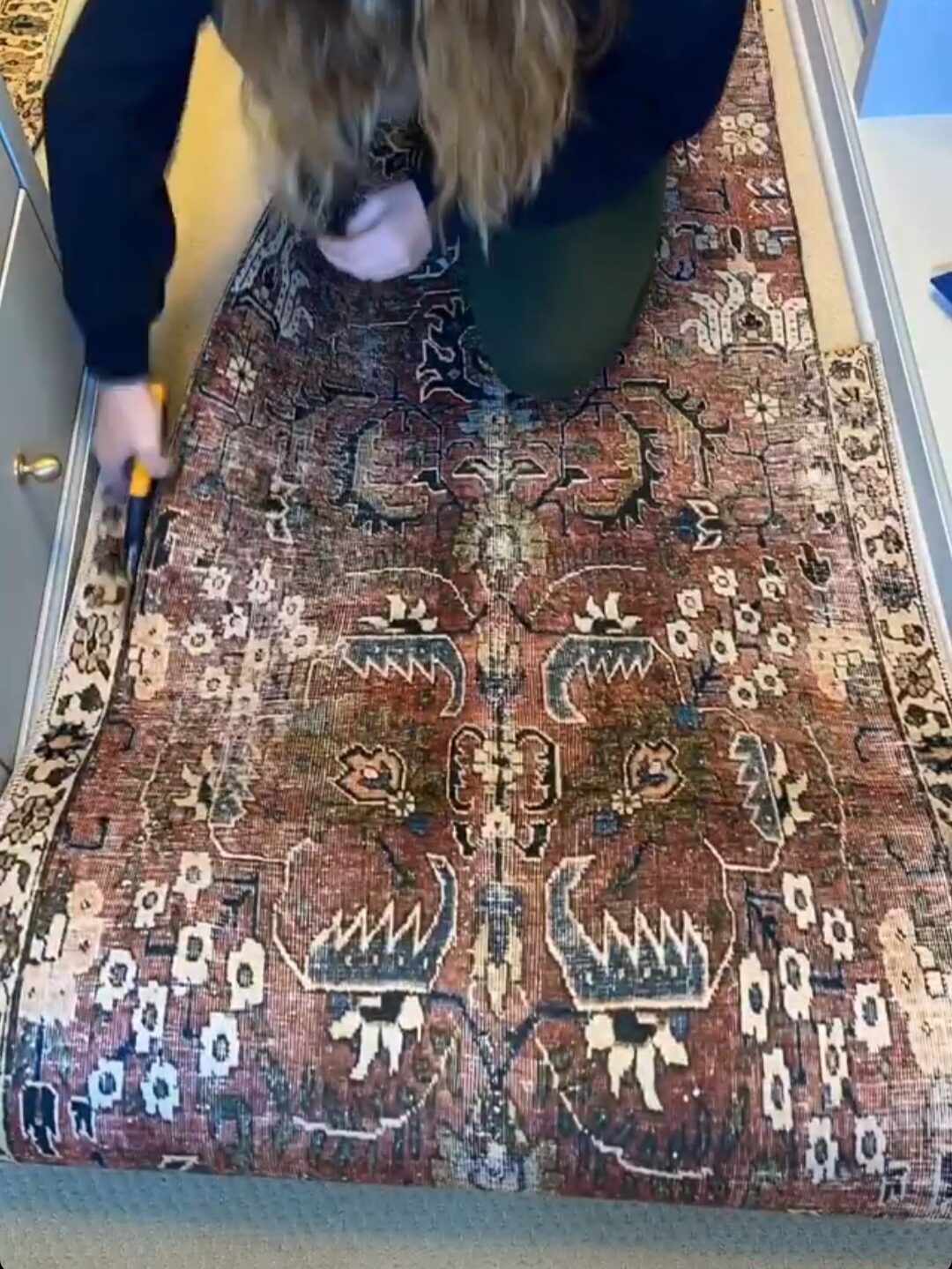 Women continue trimming the edges of a rug.